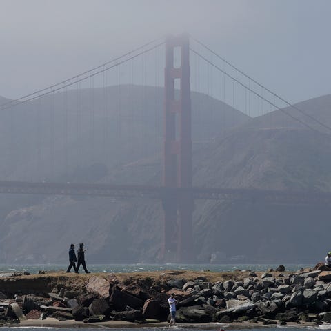 People walk on a path in front of the Golden Gate 
