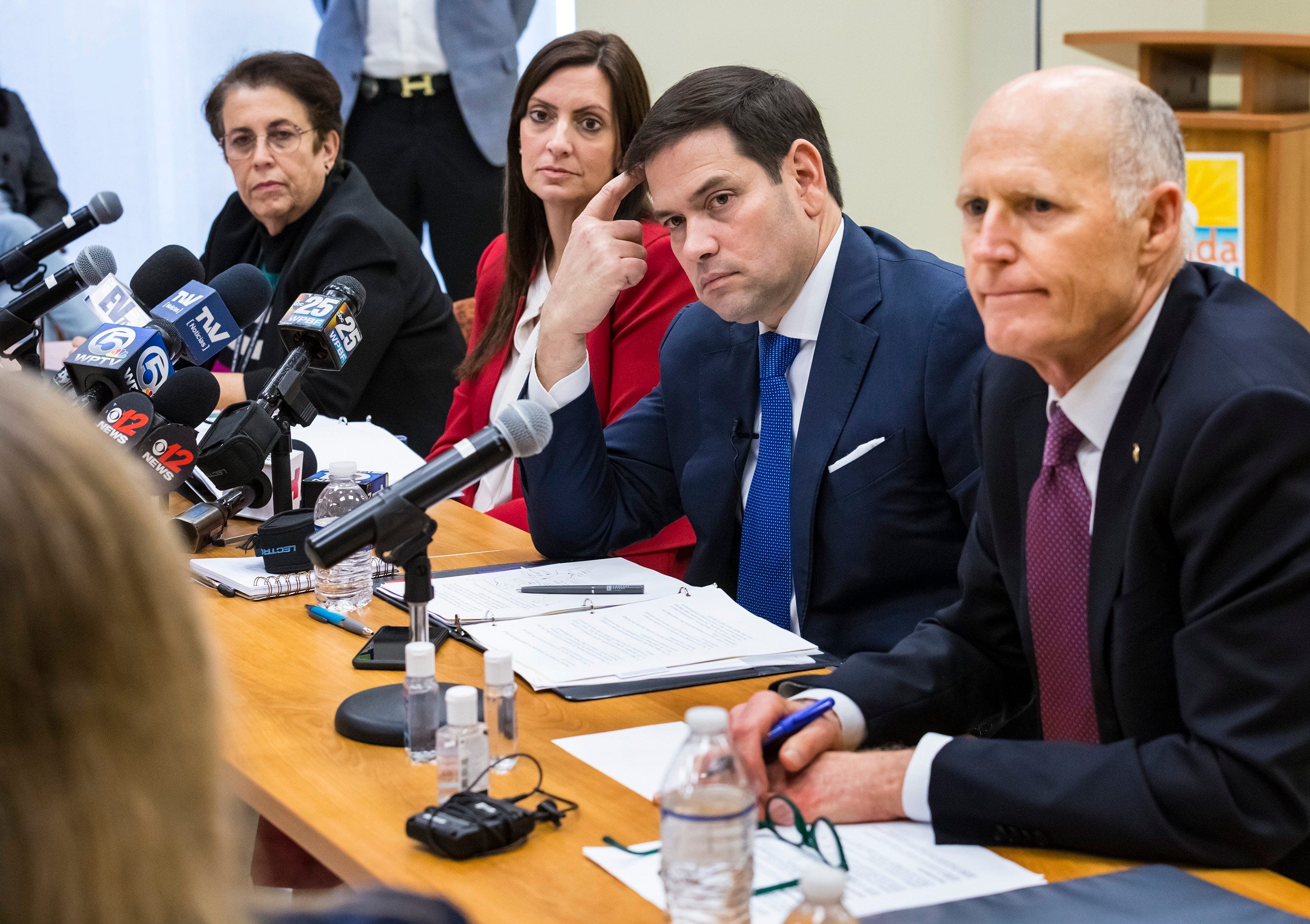 U.S. Sen. Rick Scott, right, speaks with U.S. Sen. Marco Rubio and health officials on March 6, 2020, at the Palm Beach County Health Department in West Palm Beach, Fla., As governor, Scott oversaw massive cuts in the state's health department.