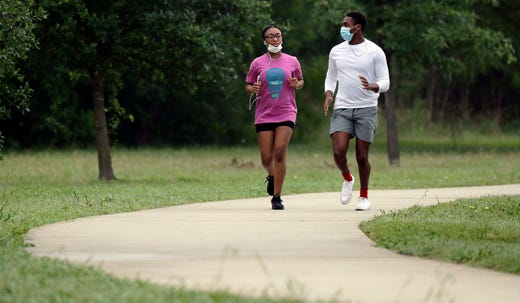 Raven Lewis (left) and brother, Ramel Lewis, wear masks as they jog in San Antonio on April 22, 2020. San Antonio remains under stay-at-home orders due to the COVID-19 outbreak and residents are required to wear face coverings or masks whenever in public.