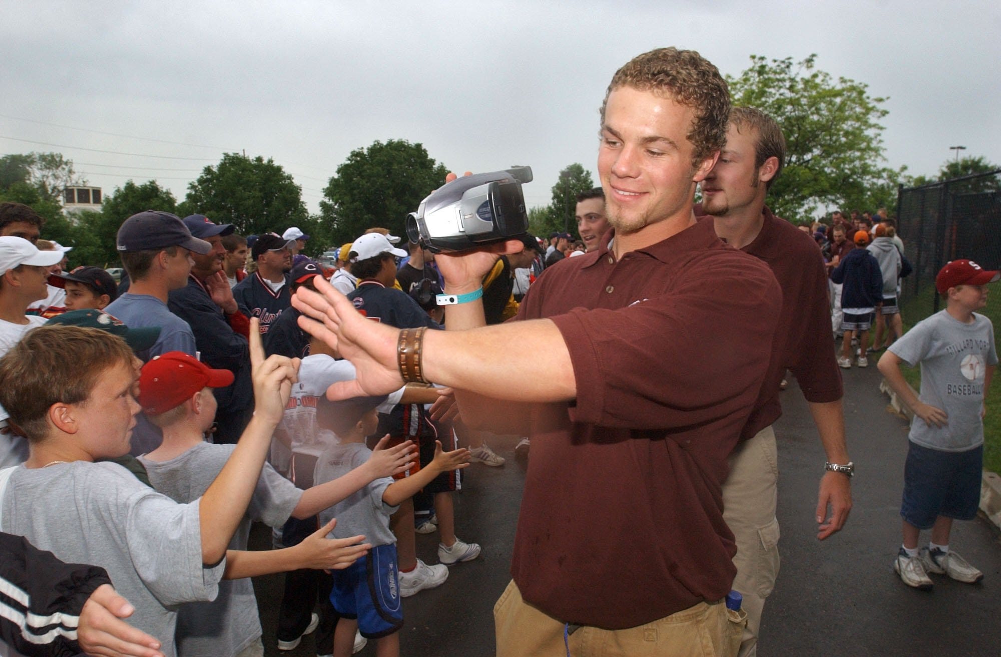 SMS catcher Tony Piazza videotapes the team's entrance to Rosenblatt Stadium as he collects high fives from fans Thursday evening before an autograph session and opening ceremonies for the College World Series.
