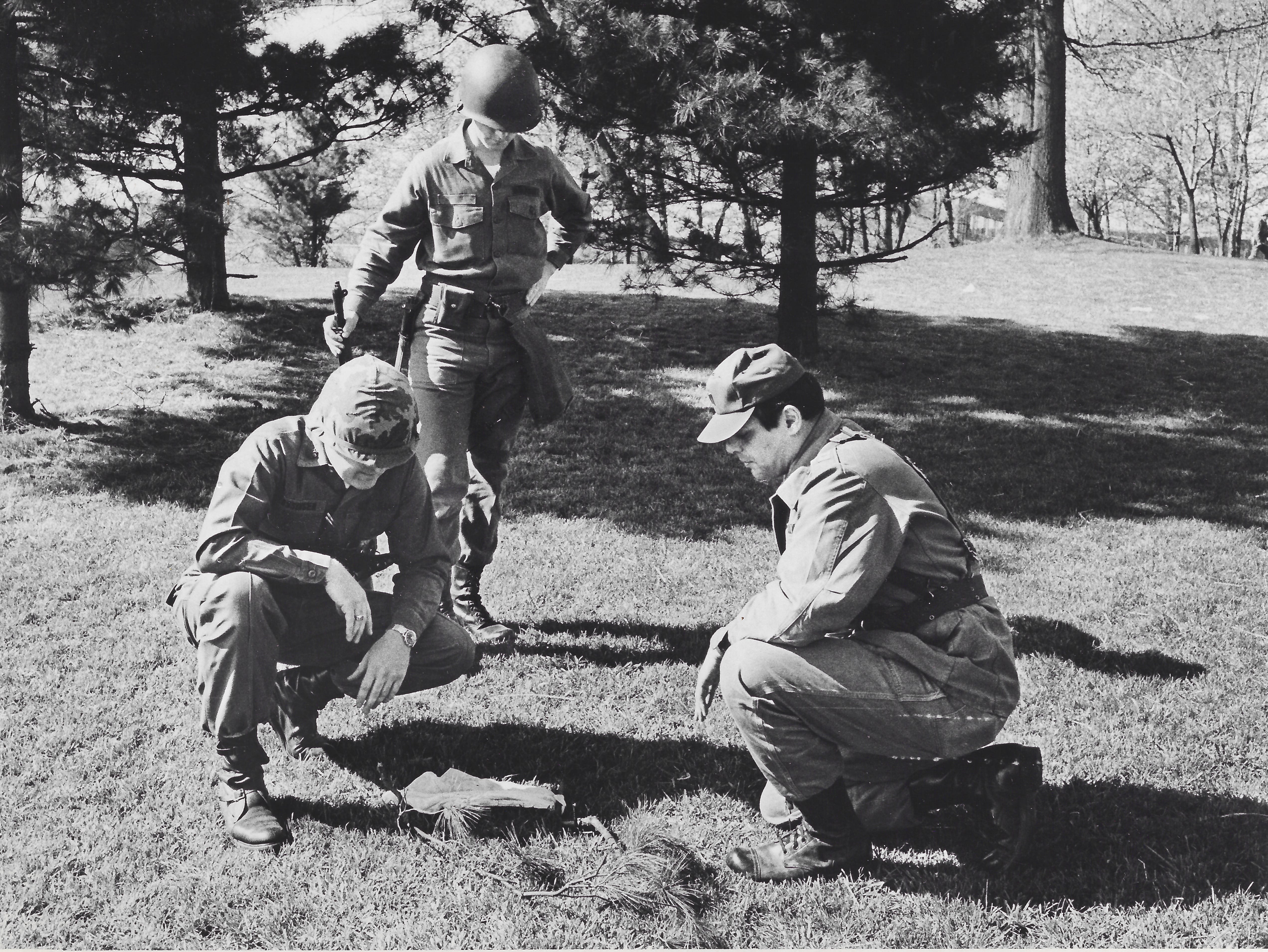 National Guardsmen look at bullet marks in the turf of Blanket Hill on May 5, 1970. The men went through the area, marking everything that might have been a bullet mark for the ballistic experts. Kneeling at left is Lt. Col. Charles Fassinger, the troop commander.