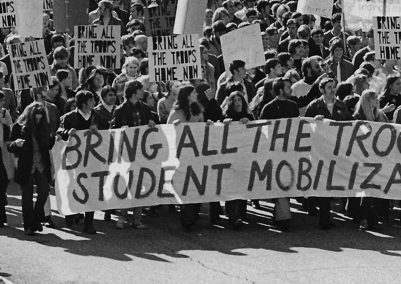 Nearly six months before the National Guard shootings at Kent State, Allison Krause helps hold a sign protesting the Vietnam War during a Moratorium Day march in downtown Kent on October 15, 1969. Krause is holding the banner above the word “ALL.” [BILL HUNTER/BEACON JOURNAL]