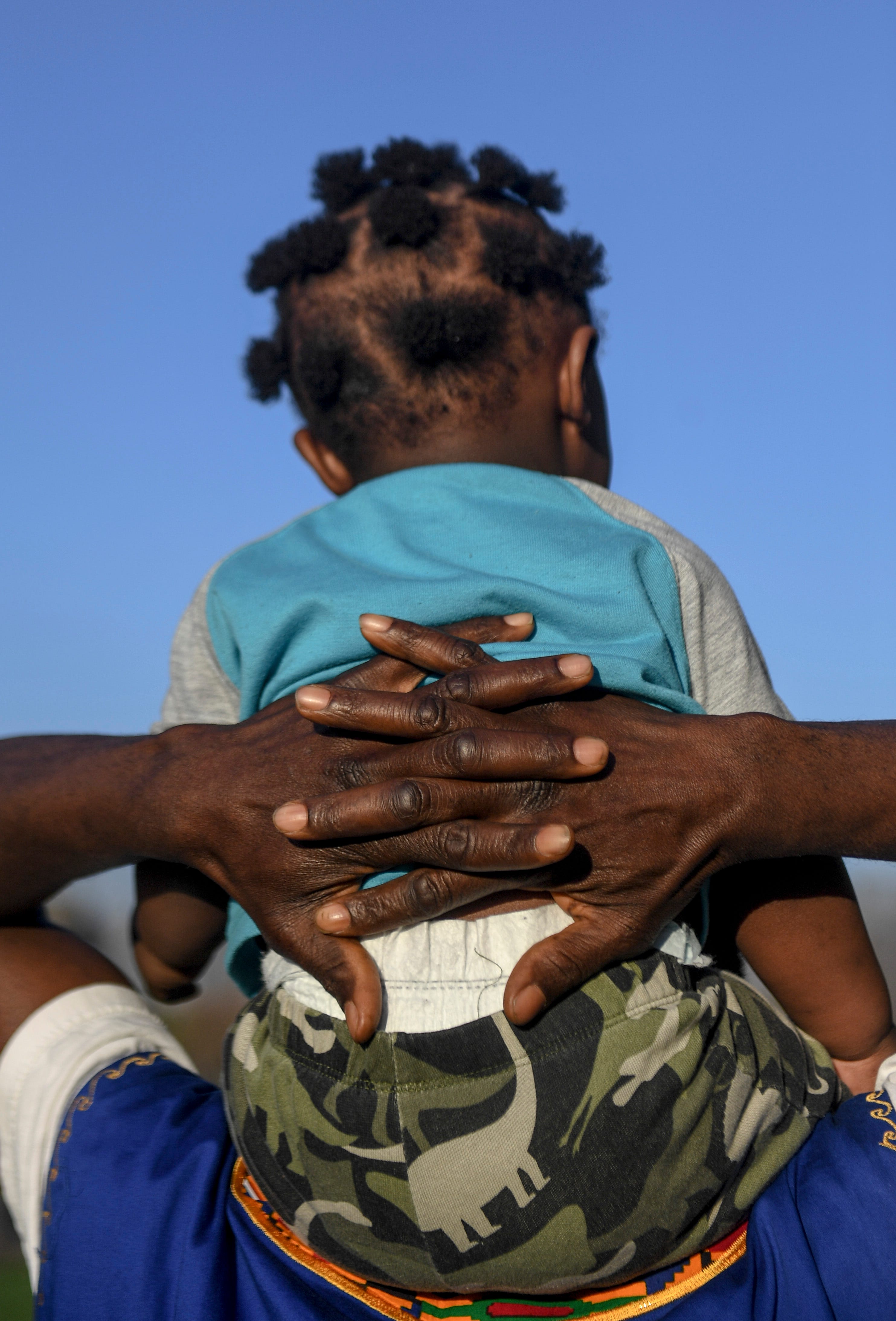 John Deranamie carries his youngest son, Nehemiah Deranamie, 1, on his shoulders in Sioux Falls, S.D. His back and shoulders have had a break from the tiring work he does as 