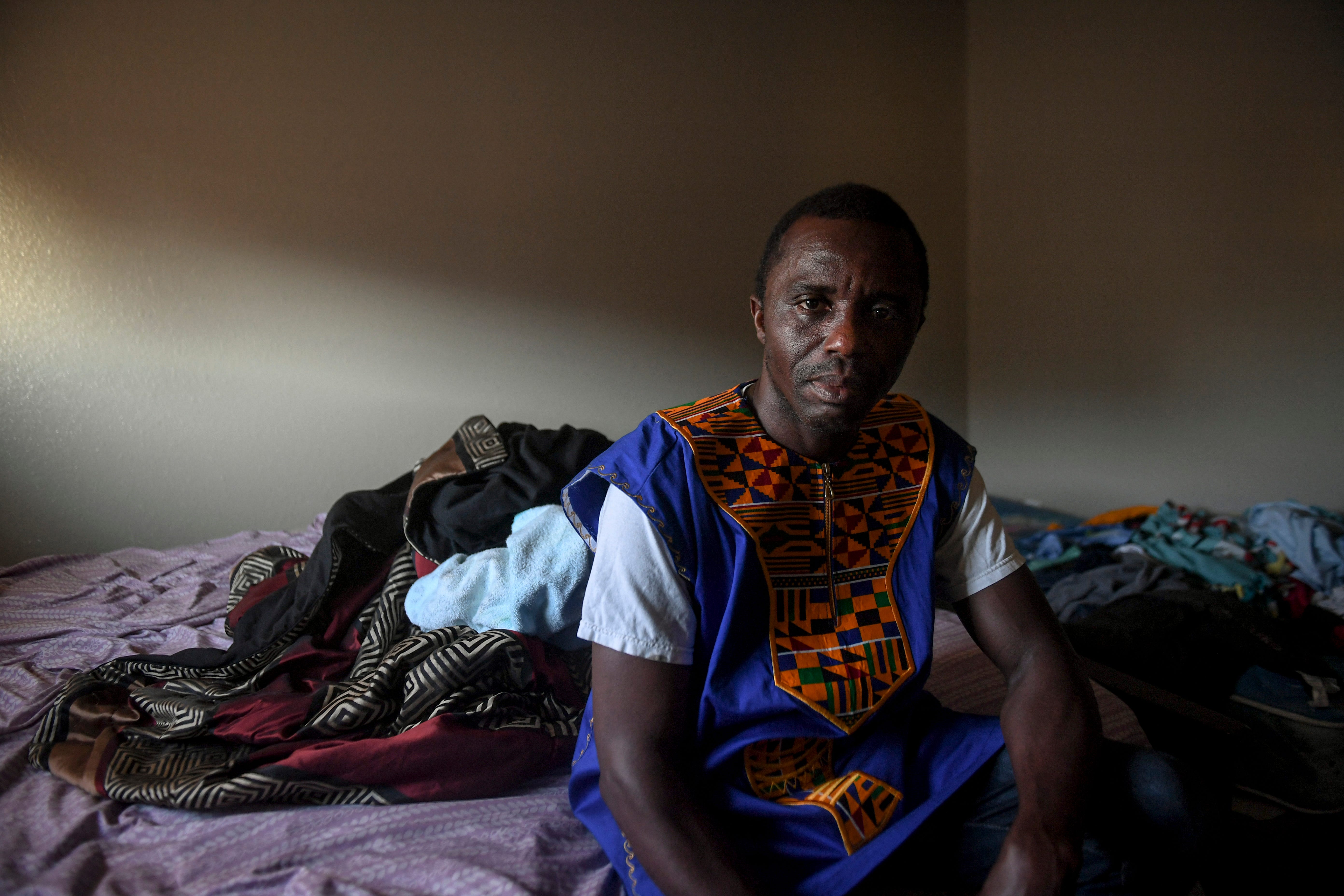 John Deranamie, a Smithfield Foods employee, poses for a portrait in the room he self-quarantined in after testing positive for COVID-19 on Wednesday, April 29, 2020 at his home in Sioux Falls, S.D. He has been spending time at home with family since the meatpacking plant shut down. "I was forced to go to work," he said. "Even though I knew it was a dangerous situation at work, I still had to go to work because I have to support my family and my people in Africa."