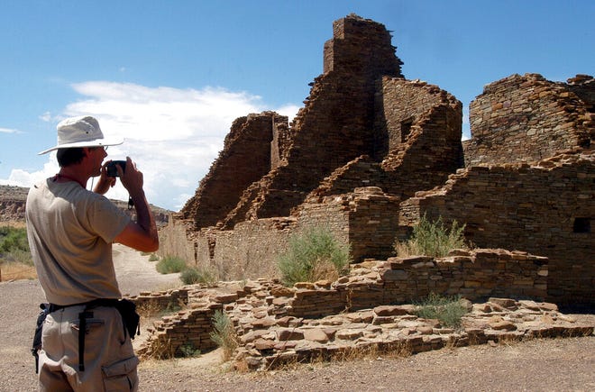 FILE - In this Aug. 10, 2005 file photo, tourist Chris Farthing from Suffolks County, England, takes a picture of Anasazi ruins in Chaco Culture National Historical Park in New Mexico. The preservation and protection of Native American cultural sites would be a priority of U.S. land managers under one of the options up for consideration as they work to amend an outdated guide for management of oil and gas drilling across a sprawling area of northwestern New Mexico. (AP Photo/Jeff Geissler, File)
