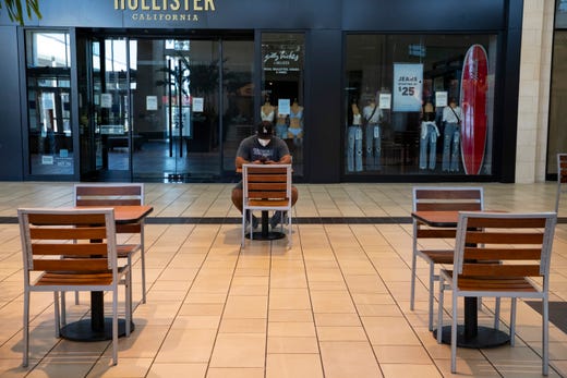 A man in a mask sits at a table at the La Palmera Mall on Friday, May 1, 2020 the first day it has been open since the COVID-19 outbreak. 