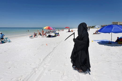 Dressed as the Grim Reaper, Florida Attorney Daniel Uhlfelder talks with reporters after walking the newly opened beach near Destin, Fla on Friday, May 1, 2020. Uhlfelder was protesting the Walton County (Florida) Commission's decision to reopen the county's beaches in spite of the COVID-19 pandemic.  “In these circumstances, I can see no rational reason to open our beaches, effectively inviting tens of thousands of tourists back into our community” Uhlfelder said in a news release. “If by dressing up as the ‘Grim Reaper’ and walking our beaches I can make people think and potentially help save a life – that is the right thing to do.” 