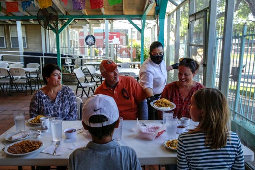 Elia Montoya places breakfast dishes in front of Carrah Roy and her family, including her husband, U.S. Representative Charles Eugene "Chip" Roy, and their kids Virginia, 9, and Charlie, 10, along with director of operations for Roy, Jennifer Carter, at Juan In A Million located on East Cesar Chavez Street in Austin on Friday, May 1, 2020. This is the first phase of Gov. Greg Abbott's order to gradually reopen Texas businesses amid the coronavirus outbreak. All retail stores, malls, restaurants, movie theaters, libraries and museums must limit customers to 25% of their listed occupancy. 