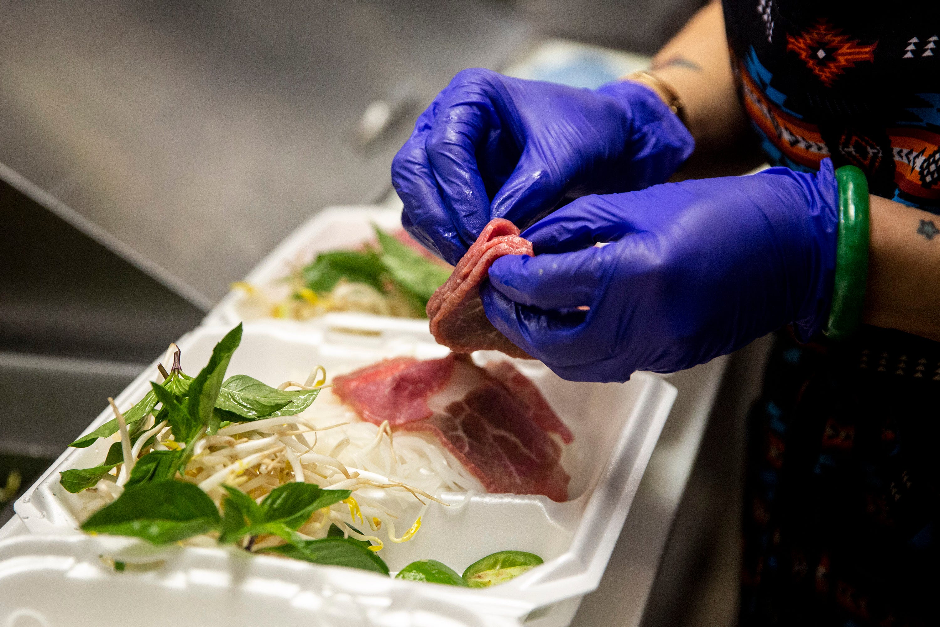 Brenda Tran prepares a to-go order of pho in the Vietnam Cafe kitchen May 3, 2020, at the Merle Hay Mall food court in Des Moines, Iowa. Pho is one the cafe's most popular dishes.