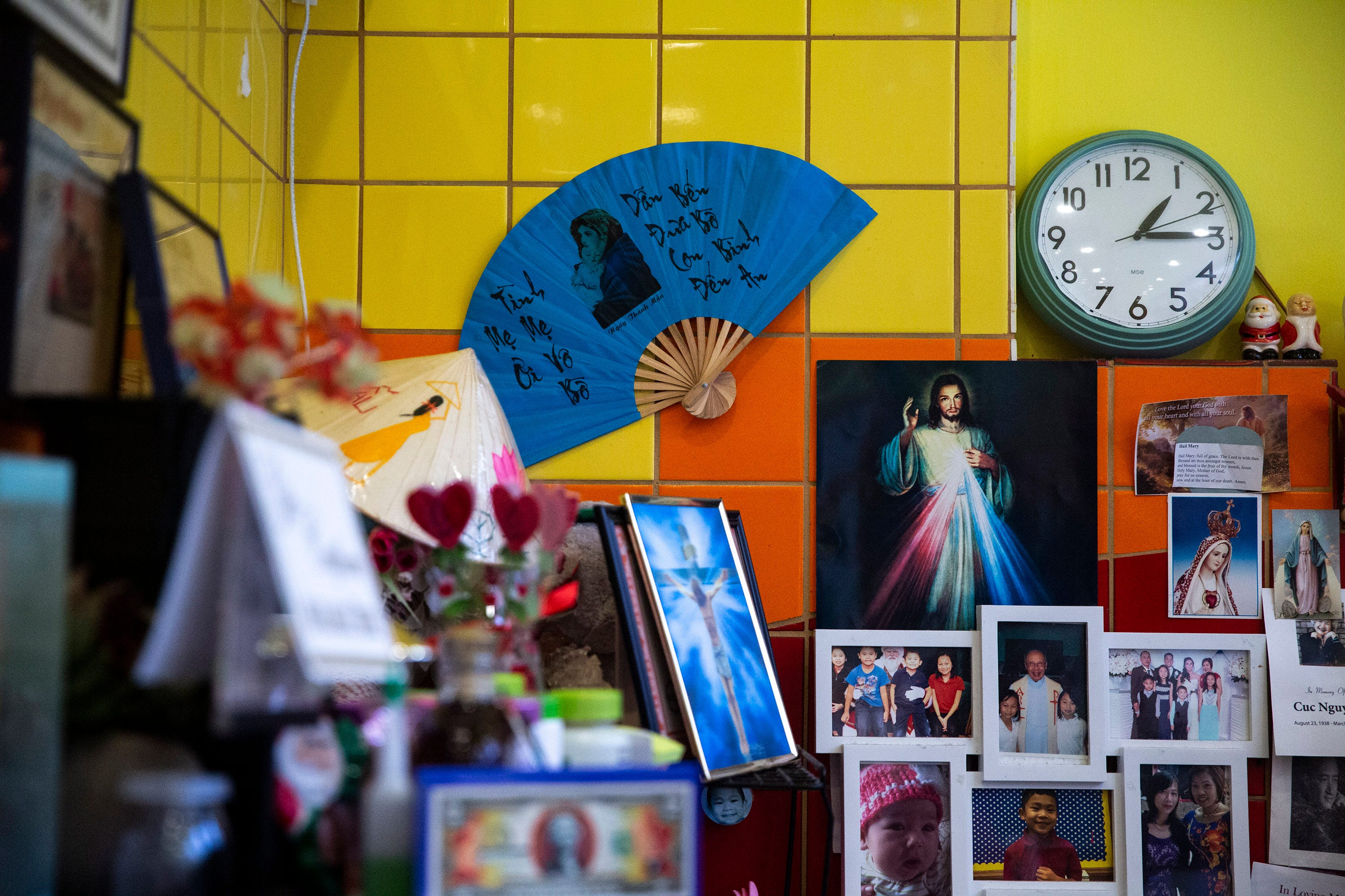 Brenda Tran displays her “angels” — photos and funeral programs of departed friends and customers with a big photo of her father in the center at Vietnam Cafe.