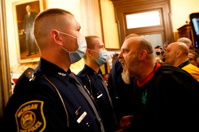 Michigan State Police bar protesters from entering the chambers of the Michigan House of Representatives on Thursday, April 30, during a rally for the reopening of businesses on the steps of the Michigan State Capitol in Lansing.  The group is upset with Michigan Gov. Gretchen Whitmer's mandatory closures to curtail the spread of coronavirus.