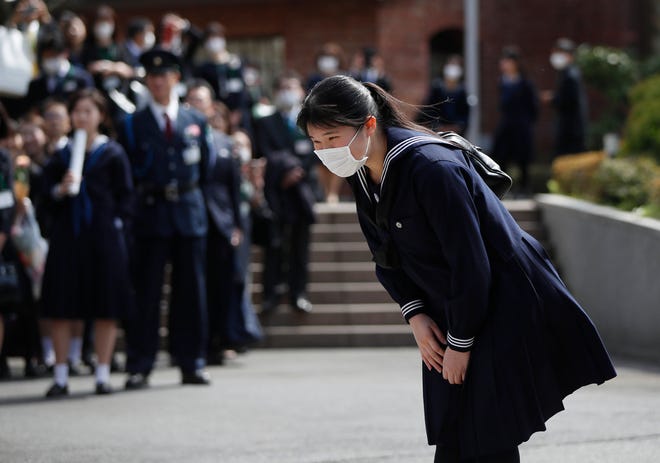 Japan's Princess Aiko, daughter of Emperor Naruhito and Empress Masako, wearing a face mask following an outbreak of the COVID-19 coronavirus, bows as she attends her graduation ceremony at Gakushuin Girls' Senior High School in Tokyo on March 22, 2020. (Issei Kato/POOL/AFP/Getty Images/TNS)