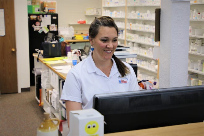 Pharmacist Ashley Seyfarth checks a prescription for a customer from behind the counter at Kare Drug in Aztec.