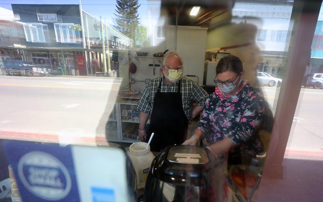 Dave Baker and daughter Sarah Watkins are seen through the front window of their Sue's Fresh Juice Bar and Sandwich Shop in downtown Port Orchard as they prepare sandwiches to go into boxed meals for the Arc of the Peninsulas on Thursday. The restaurant is participating in the Full Circle Meals program, which provides meals to people and organizations in need through donations by community members.