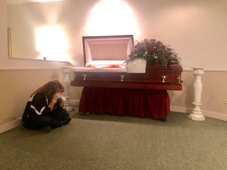 Robin Christensen, 52, cries on the floor of the Miller Funeral Home room in Sioux Falls, South Dakota after her mother, Darleen Smart, died from COVID-19 on April 29. The photo was posted on Facebook, urging people to take coronavirus safety precautions seriously.