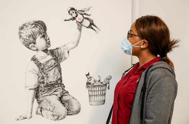A new artwork by street artist Banksy hangs in a hallway at University Hospital Southhampton in southern England, May 7, 2020. "Game Changer" is intended as a tribute NHS carers continuing to work during the COVID-19 pandemic.