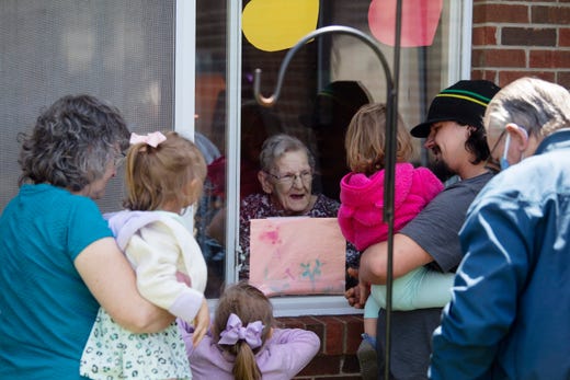 Alice Mayes, 92, is visited by her family at Signature HealthCARE on May 6, 2020 in NewBurgh, Ind. The family, from left, Onya Rhoades, Lexi Rhoads, 3, Dylan Rhoades, 5, Kaitlyn Helmbrecht, 2, James Helmbrecht and Del Mayes were separated by a window glass on May 6, 2020 in Newburgh, Ind. The 92-year-old is a COVID-19 survivor.