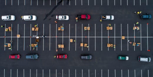 People affected by the coronavirus pandemic line up in their cars at Central Texas Food Bank drive-through food distribution at Del Valle High School in Austin, Texas, on Thursday May 7, 2020.  Hundreds received an emergency food box containing about 28 pounds of shelf stable food items.  