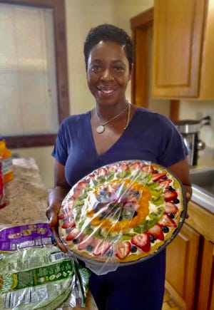 A slimmed-down Bridgett Wilder holds a fruit pizza created by fellow dietitian Angie Wilkes Tate at one of her nutrition classes.