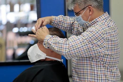 William Romero cuts George Atkins' hair after a long closure due to coronavirus. Markham Salon at 2200 N. Yarbrough reopened Friday to the delight of many who visited the salon.