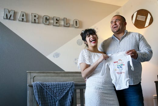Marcos and Valerie Garcia hold a onesie that reads, "hand picked for earth by my brother in heaven," at their home Thursday, May 7, in El Paso. The Garcias lost their first child, Marcelo, to SIDS in December of 2019. They found out they were pregnant again in early March. The Garcias suffered a tremendous loss but said that they believe Marcelo will watch over their family as they continue to grow.
