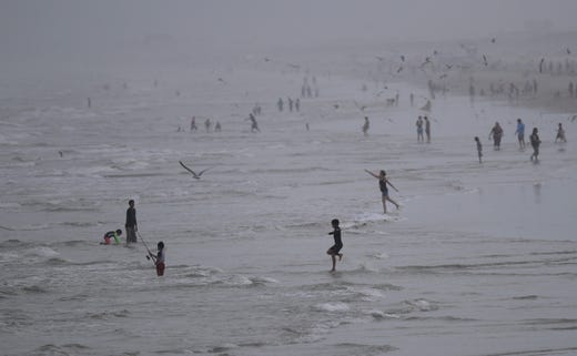 Beachgoers play, swim and fish at dusk Friday, May 8, 2020, in Port Aransas, Texas. Texas' stay-at-home orders due to the COVID-19 pandemic have expired and Texas Gov.