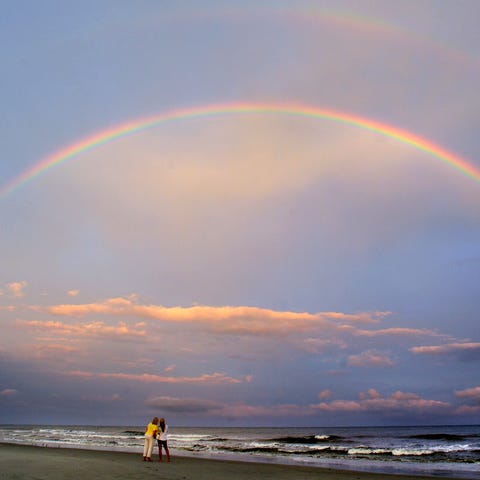 Beachgoers admire a double rainbow that appeared o