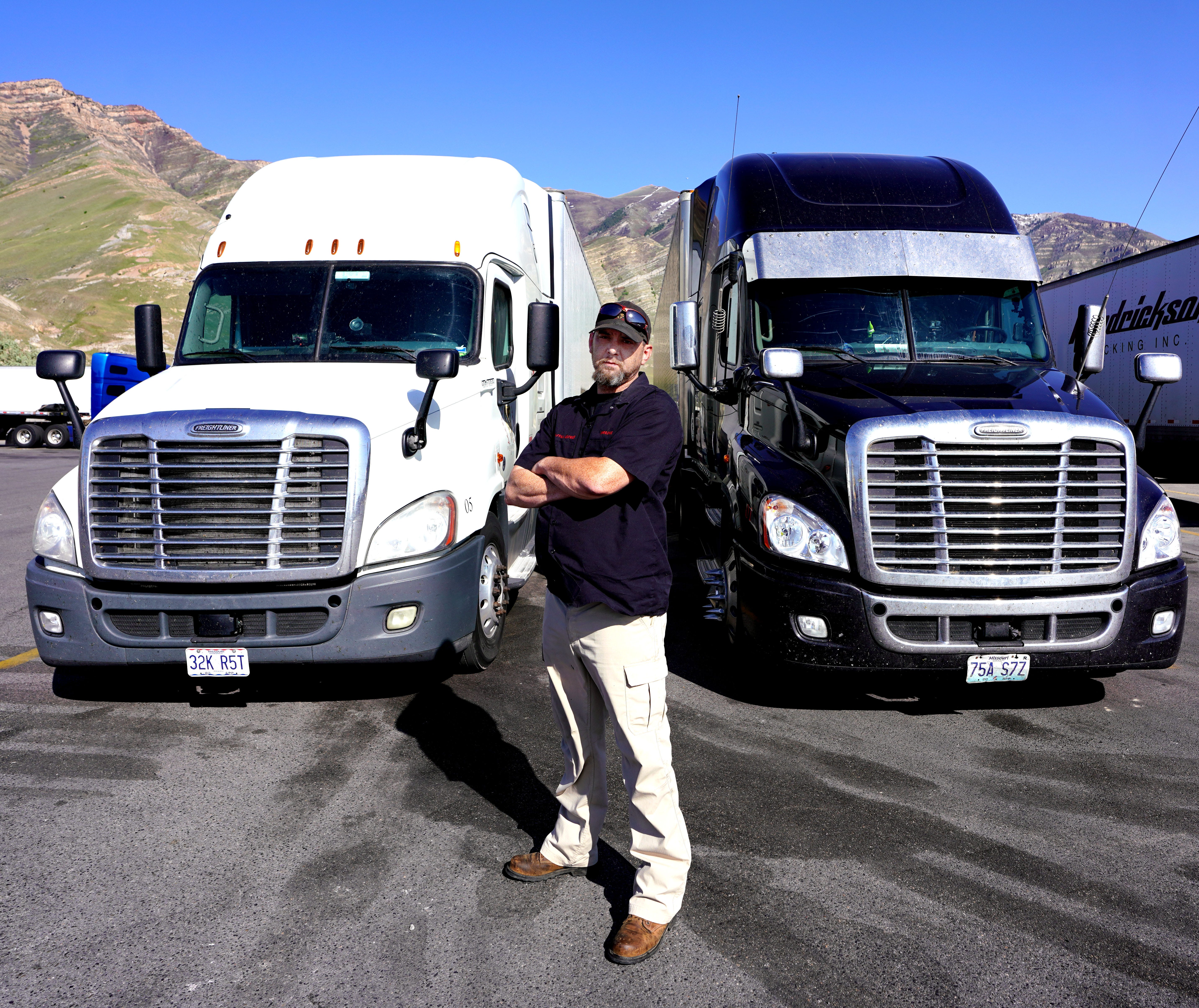 Trucker James Rodgers stands in front of two of his trucks at a truck stop outside Salt Lake City.