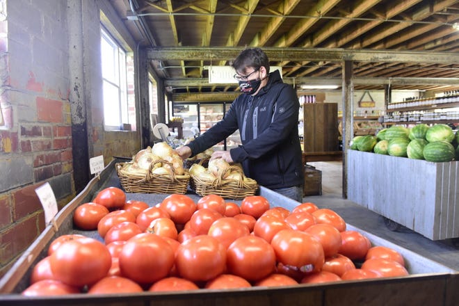 Chris Schimpf of Pickwick Place stocks a few onions Wednesday during the shop's first day of business.