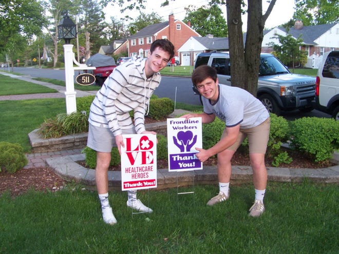 Jesse Lang, left, and brother J.R.. post signs that their Haddon Township family designed and had manufactured to sell to homeowners for the benefit of front line workers in the fight  against the coronavirus pandemic.