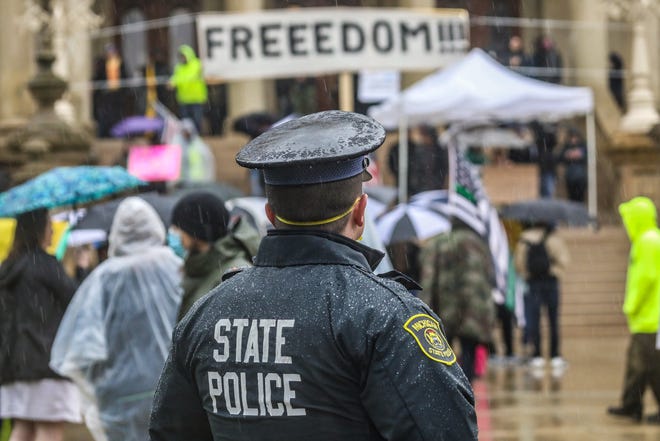 Michigan State Police look on during the a protest rally against Gov. Gretchen Whitmer's order to stay home during COVID-19 pandemic in Lansing, Mich. on Thursday, May 14, 2020. 