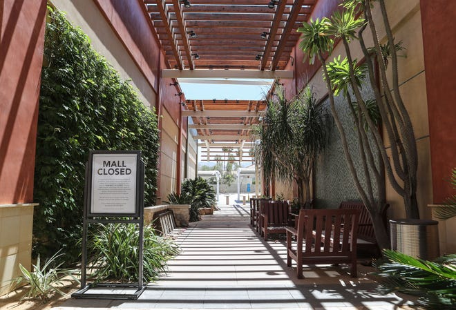 A sign informs people that the mall is closed in an empty walkway in a normally busy spot on El Paseo Drive in Palm Desert, May 13, 2020.