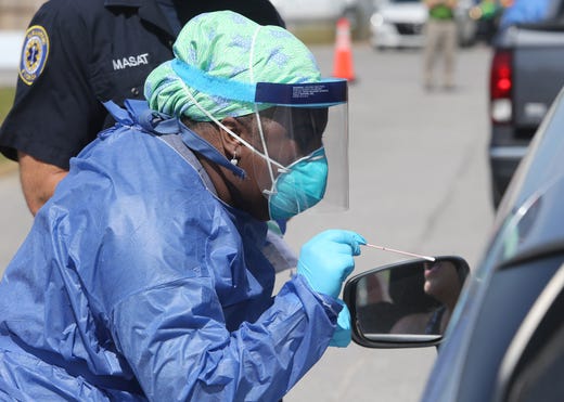 Shandrika Pritchett with the Walton County Health Department administers a COVID-19 test at a drive-thru testing station set up at the Van R Butler Elementary School on May 14 in South Walton County, Fla.