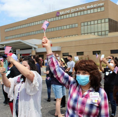 Most still wearing masks even outside, Abilene Regional Medical Center employees including Abby Boyd (left, Human Resources generalist, and Tonya Anderson, Ethics and Compliance director, wave a quick goodbye to a Dyess B-1B bomber as it flew over and then south of the hospital Friday. Some recorded the fly-by on their cellphones. May 15 2020