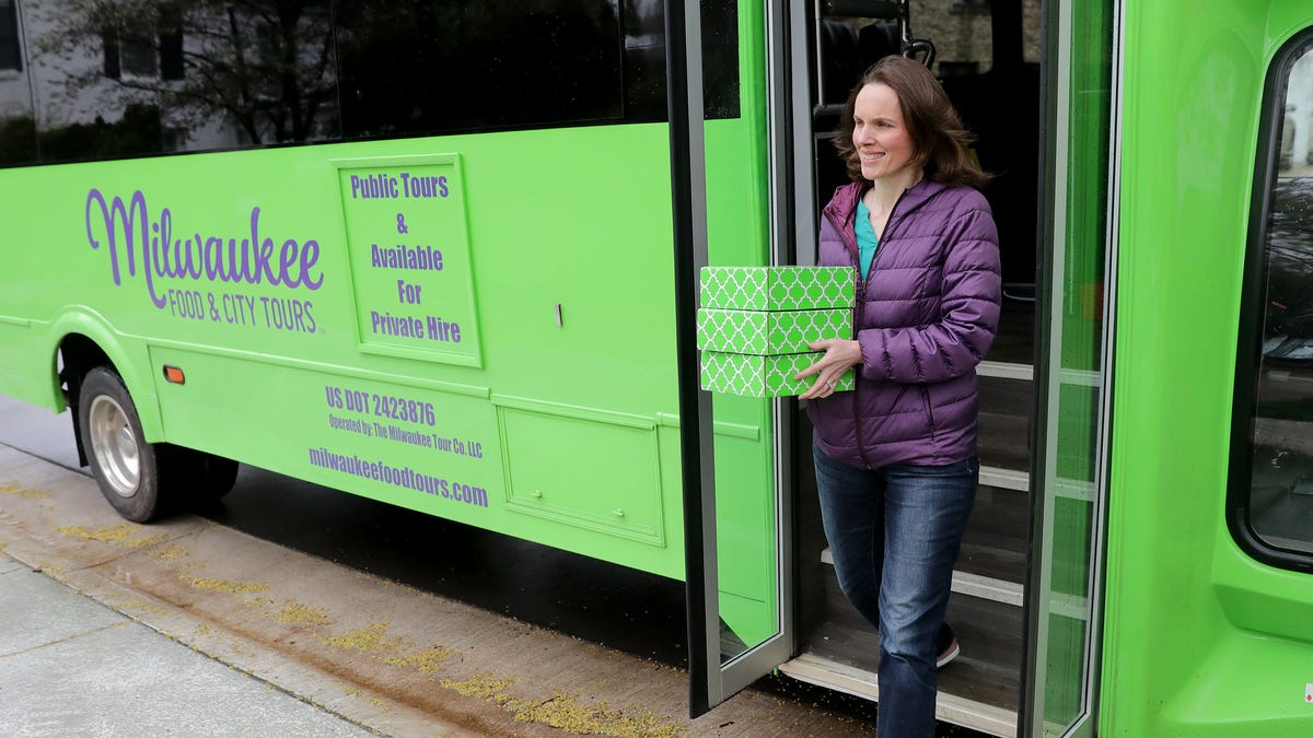 Theresa Nemetz, founder and chief experience officer of Milwaukee Food & City Tours, carries boxes of care packages on Thursday. Milwaukee Food & City Tours can't load up buses of strangers to take them on a tour of Milwaukee, so it's created care packages with local items that can be delivered to customers' doors.