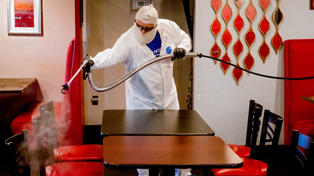 Joe Barnes, owner of Safe Spray Services, sprays disinfectant at Rococo restaurant as he treats and cleans the surfaces on Friday, May 15, 2020, in Oklahoma City, Okla. Barnes turned his grease traps cleaning service to a COVID-19 deep-cleaning service, that includes disinfectant spay, clean-up and UV ray treatment, to contribute to the pandemic response and keep his employees paid.