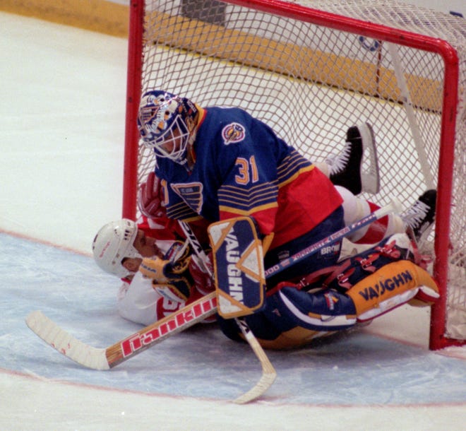 St. Louis Blues goalie Grant Fuhr lands on a sliding Red Wings' Steve Yzerman after deflecting a shot away during the first period in Game 2 of the Western Conference quarterfinals at Joe Louis Arena, April 18, 1997.