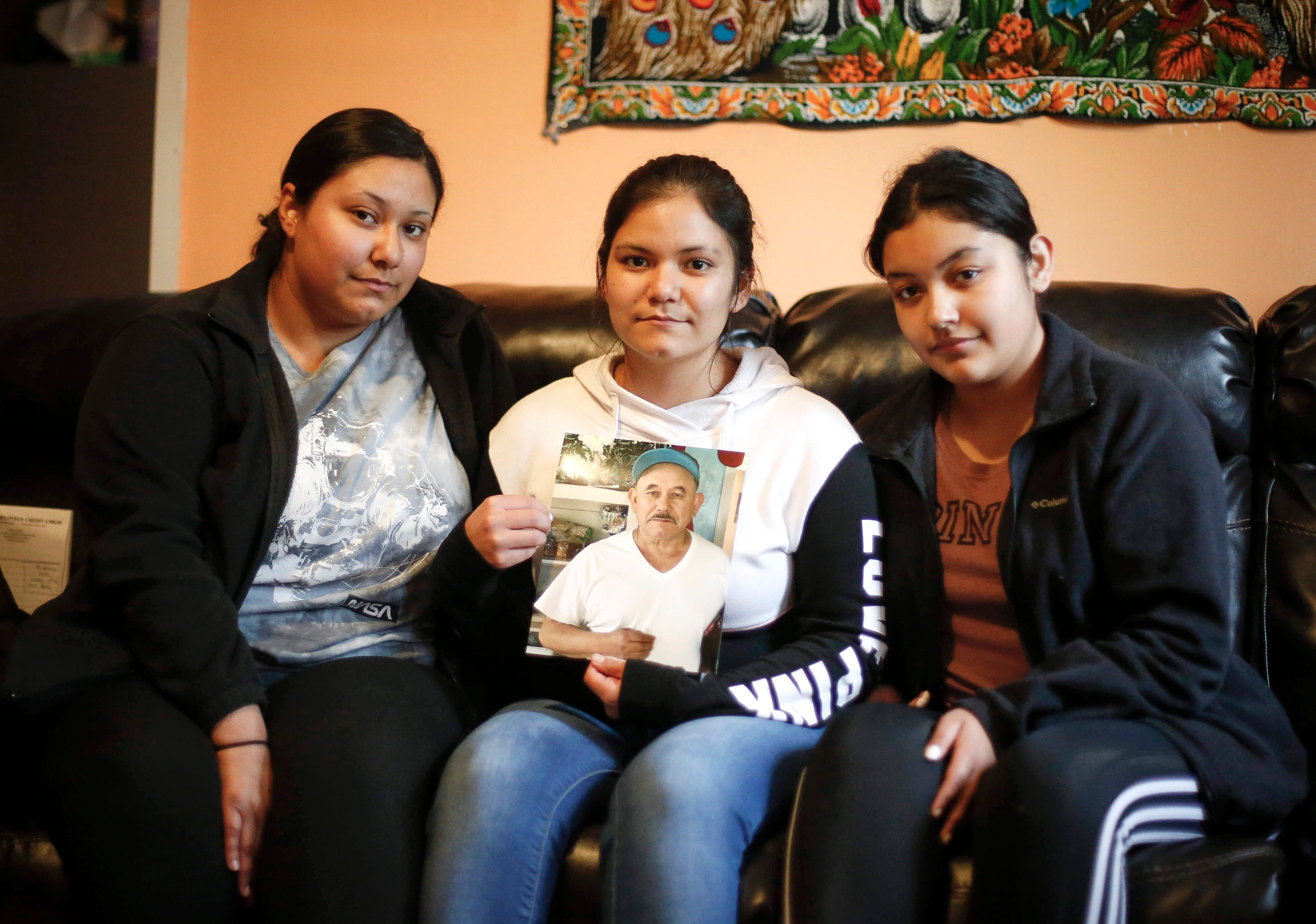 Maria Andrade holds a photo of her father, Jose Andrade Garcia. Maria, her sister Alejandra (left) and Jose's granddaughter Diana lost Jose in May after a monthlong battle with COVID-19.