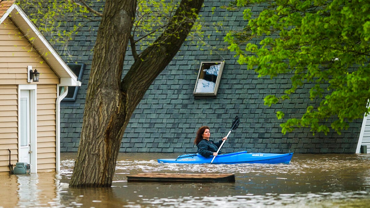People use kayaks to assess the damage at homes in their neighborhood on Oakridge Road on Wixom Lake, Tuesday, May 19, 2020 in Beaverton, Mich.