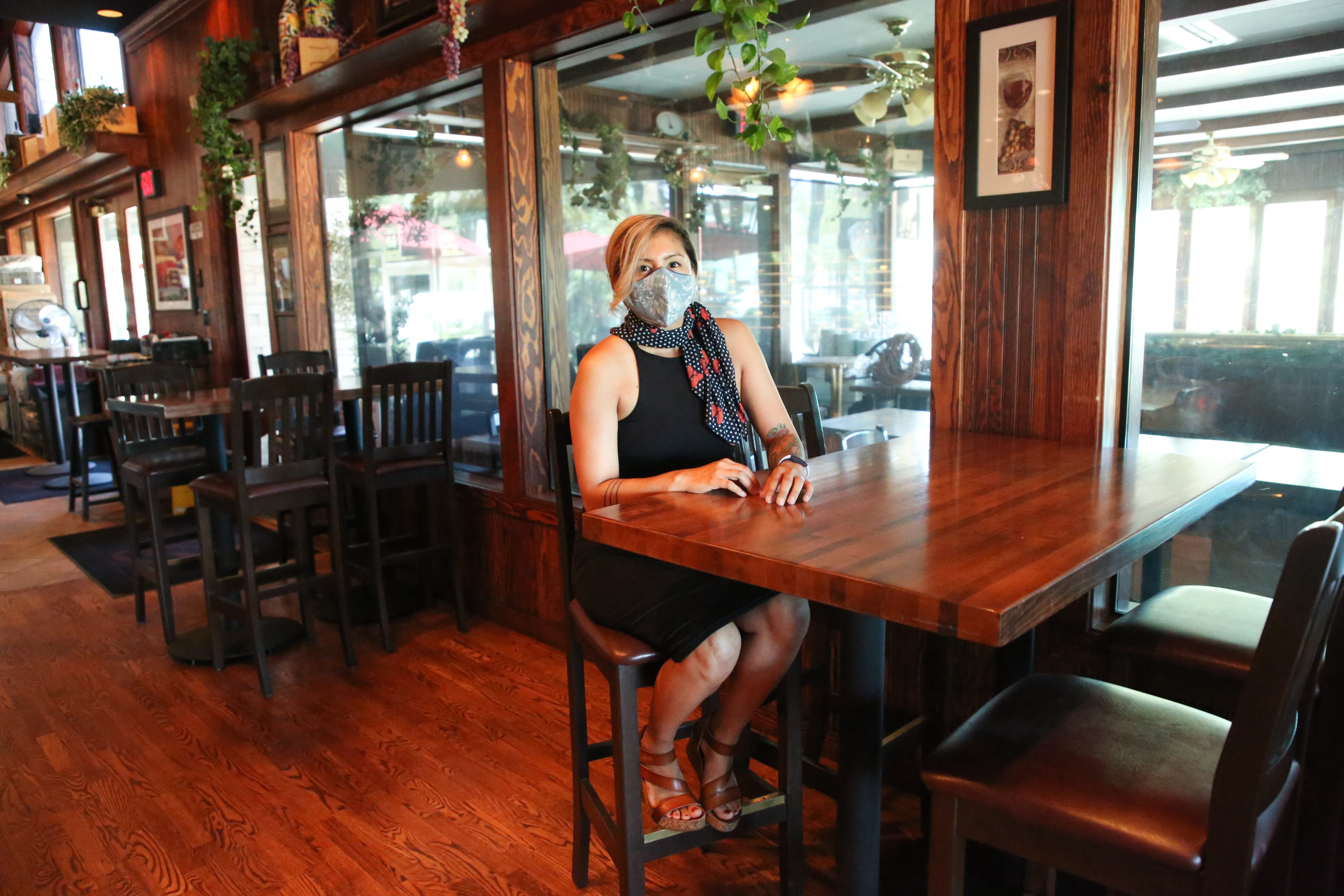 Antonia Harrington, general manager of Enzo's Bistro and Bar in La Quinta, Calif, sits at the high-top bar area seating on Wednesday, May 20, 2020. Tables are positioned at a distance in anticipation of dining in being permitted once again during the coronavirus pandemic.