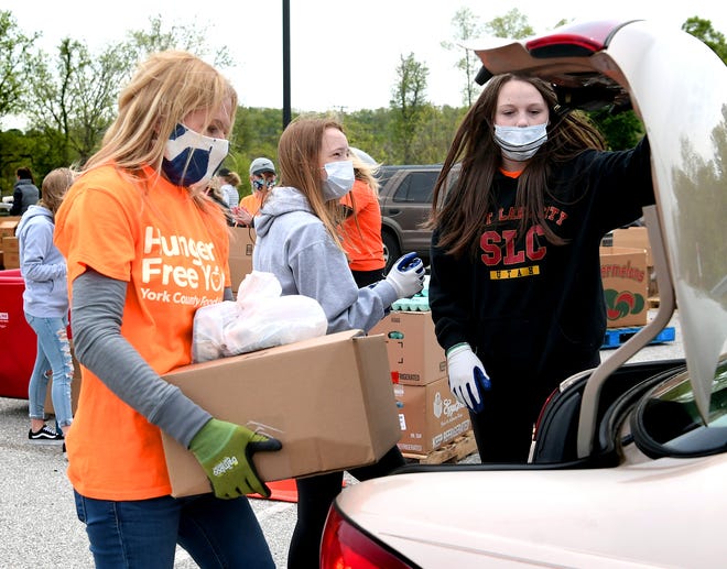 Volunteer Crystal Miller of York Township and her daughters Lainey, 14, center, and Vanessa, 15, load a trunk with food during a pop-up drive-thru food distribution at Red Lion High School Wednesday, May 20, 2020. The event was sponsored by the York County Food Bank and Community REACH, a Red Lion-based community aid organization. Bill Kalina photo 