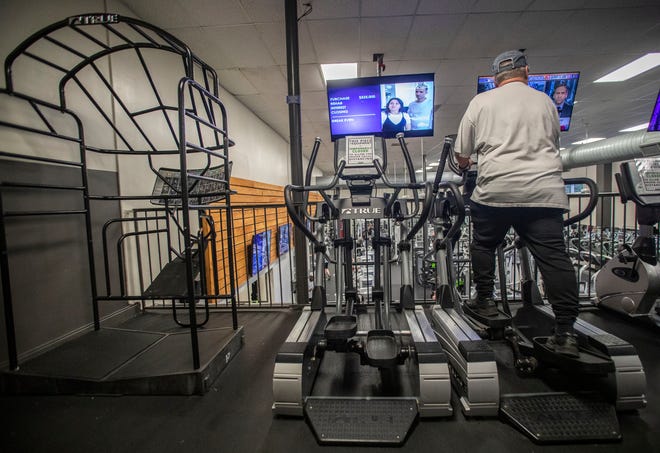 A man works out on an elliptical at Momentum Fitness. Every other cardio machine has a sign saying it is temporarily closed so everyone can practice social distancing. 