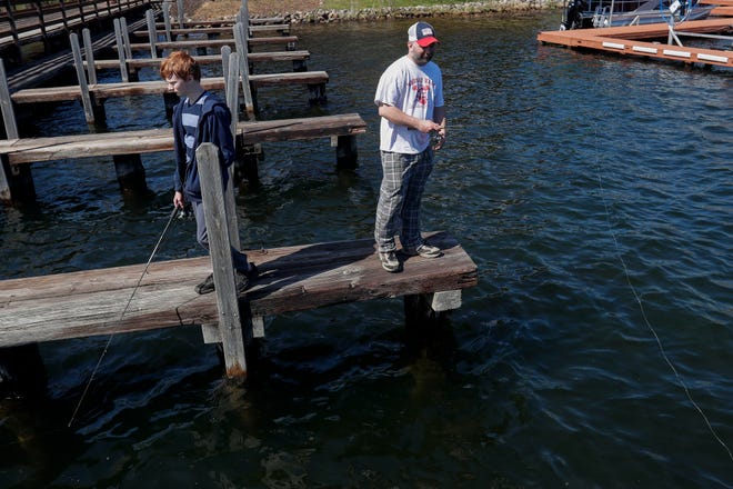 Blake Waldinger, 14, and his father, Brett, fish on Wednesday from a dock on Minocqua Lake in Minocqua.