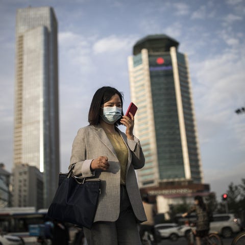 A woman wears a mask while using an iPhone in Wuha