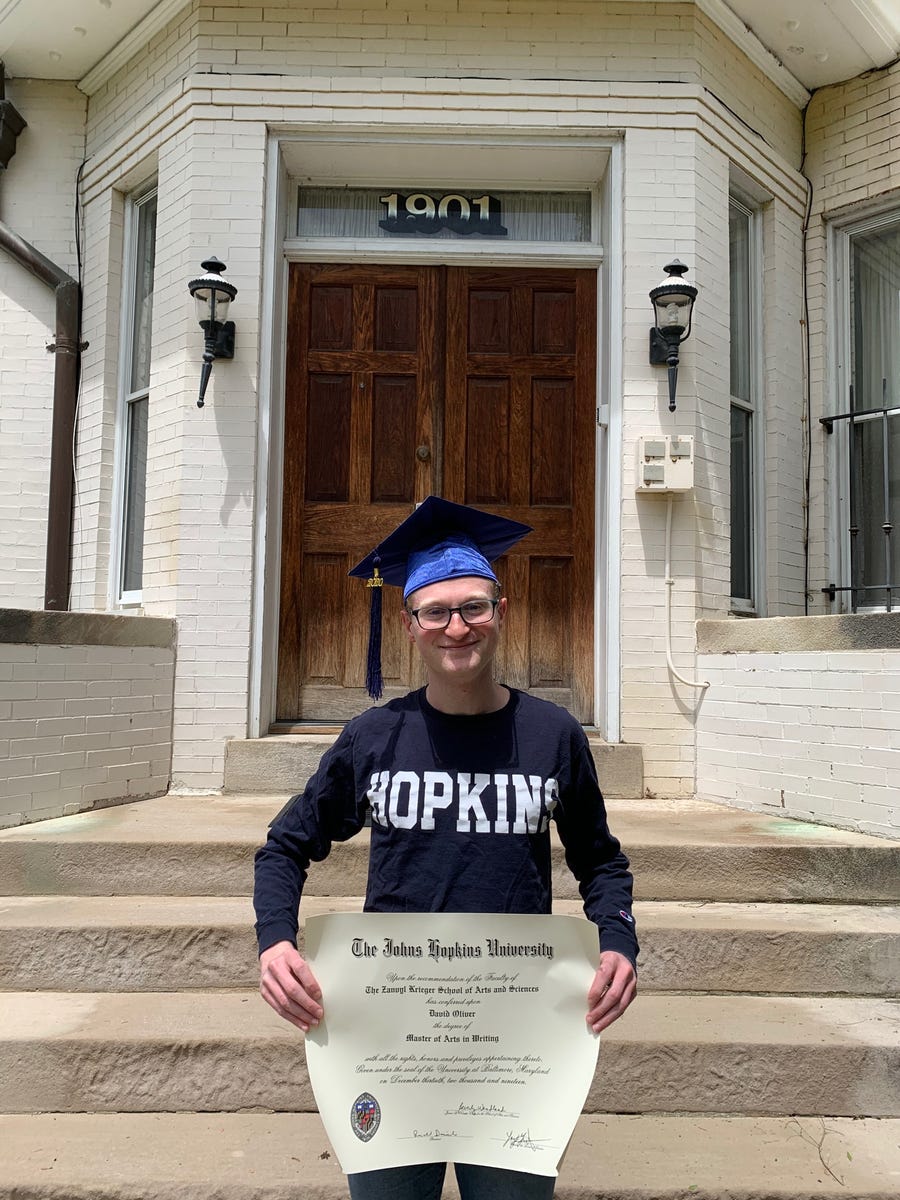 David Oliver poses for a photo taken by his roommate outside his apartment wearing his cap and holding his diploma.