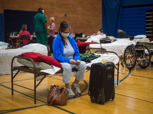 Midland resident Ritu Patel communicates with family members on her cell phone at a temporary shelter at Midland High School, Wednesday, May 20, 2020 in Midland, Mich. Patel was concerned because her husband had left the shelter to assess the flood damage to their home.