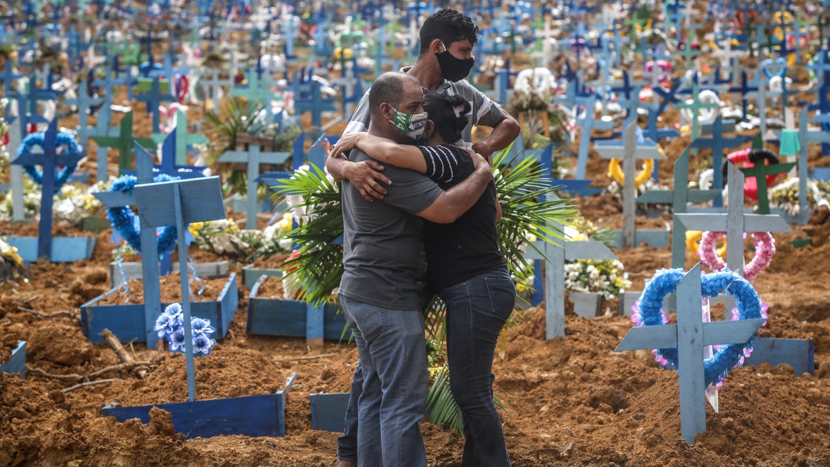 Relatives of a deceased person mourn during a mass burial of coronavirus (COVID-19) pandemic victims at the Parque Taruma cemetery on May 19, 2020 in Manaus, Brazil.  Brazil has over 260,000 confirmed cases and more than 17,000 deaths caused by coronavirus (COVID-19) pandemic.
