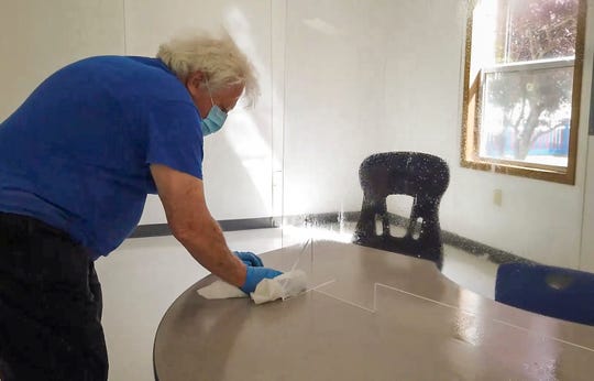 A Lakewood Public Schools custodian cleans up a desk set up with a plexiglass shield for in-person evaluations for incoming students with special needs. Incoming public schools students from any age are being tested on their learning and speech skills; evaluated for occupational and physical therapies; evaluated psychologically; and assessed for their English Language Learner level.