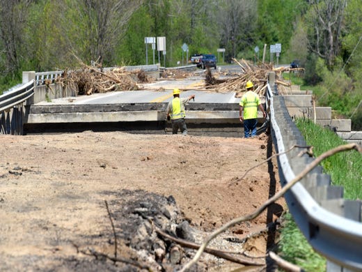 Utility workers survey the M-30 washed out bridge over the Tittabawassee River in Edenville.