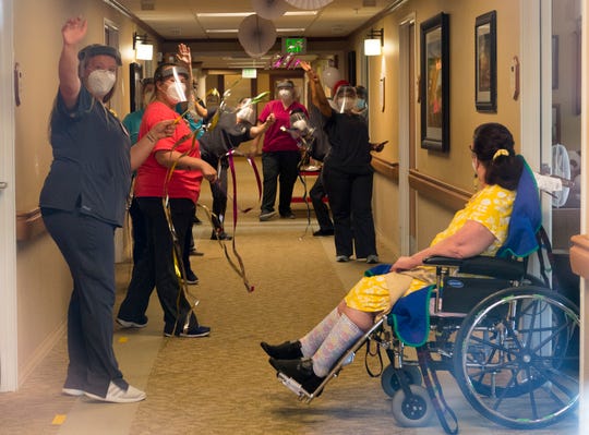 Hamilton Pointe nursing home staff wave down the hallway during a celebration parade for three residents that recovered from COVID-19 Friday afternoon, May 22, 2020.